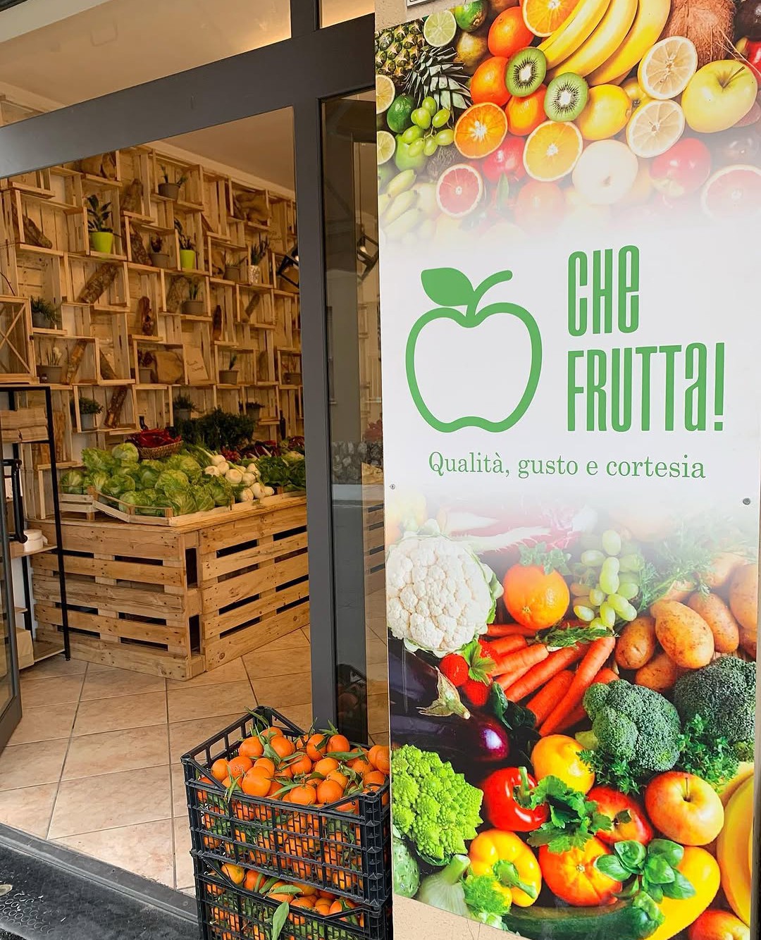 Ingresso del negozio Che Frutta! con insegna e cassette di mandarini